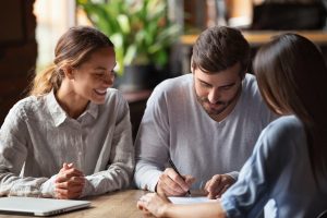 Overjoyed millennial couple feel happy closing deal put signature on agreement meeting with realtor